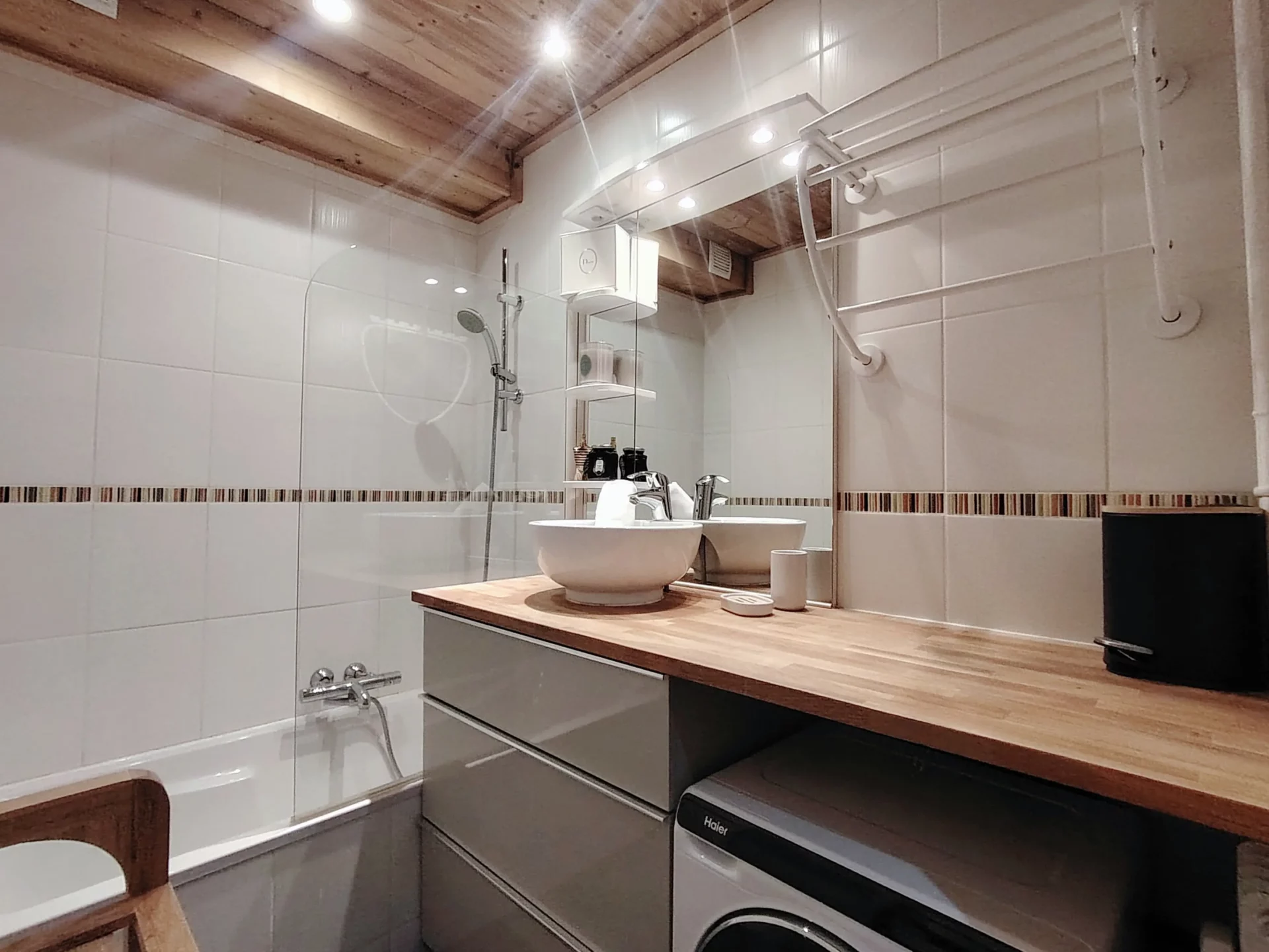 Location appartement à l'alpe d'huez - Salle de bain avec baignoire et vasque ainsi qu'une machine à laver sous le plan vasque de la salle de bain