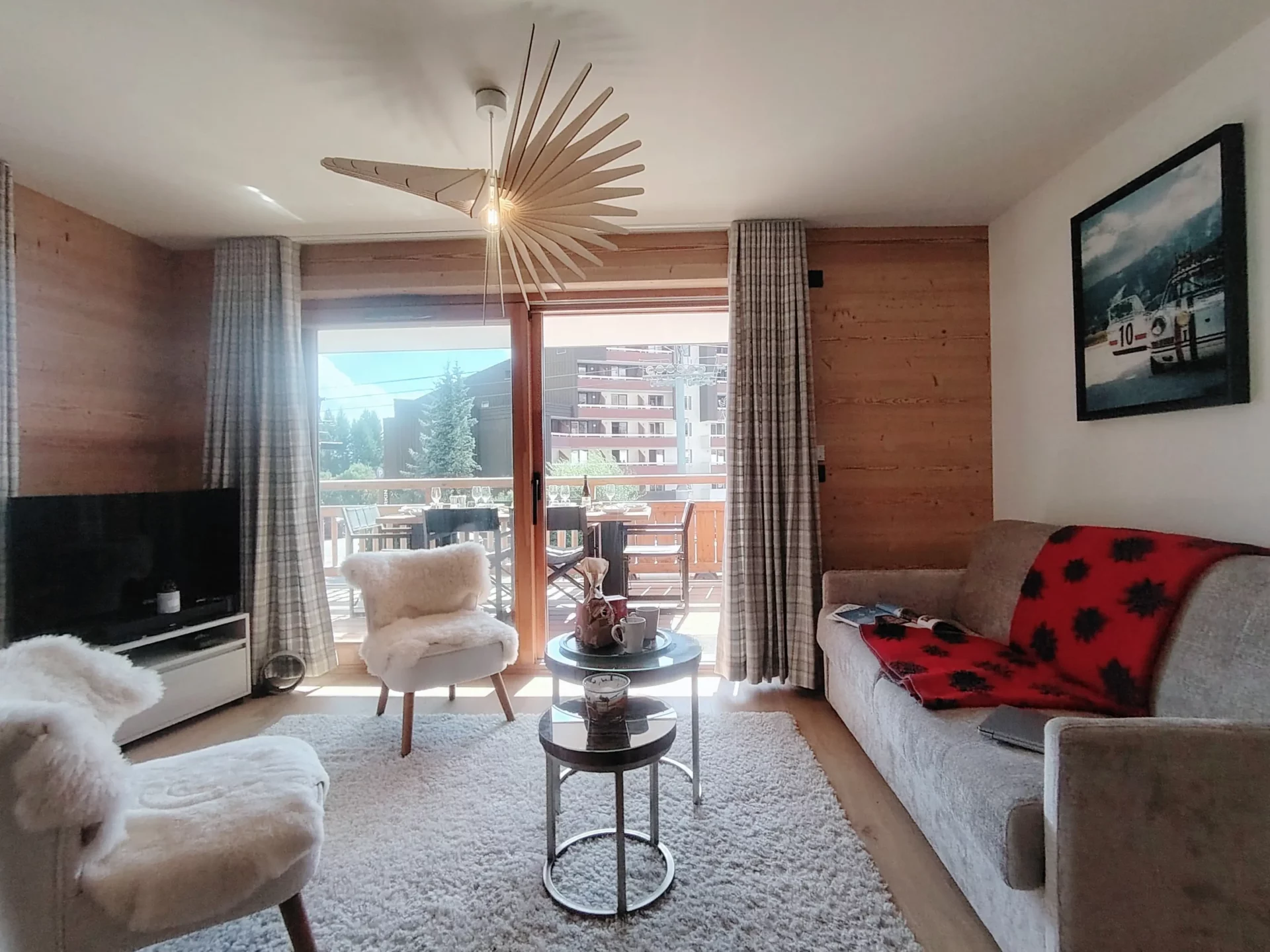 Salon chaleureux avec canapé et fauteuils, donnant accès à un balcon ensoleillé – Résidence Cachemire A105 Alpe d’Huez.