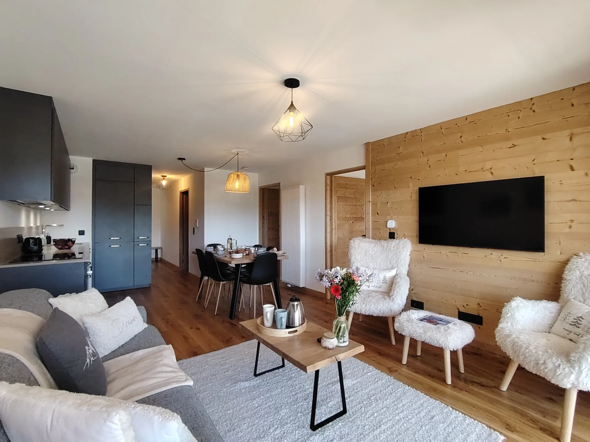Location appartement à l'alpe d'huez avec un salon, fauteuil, télévision et cuisine en arrière plan