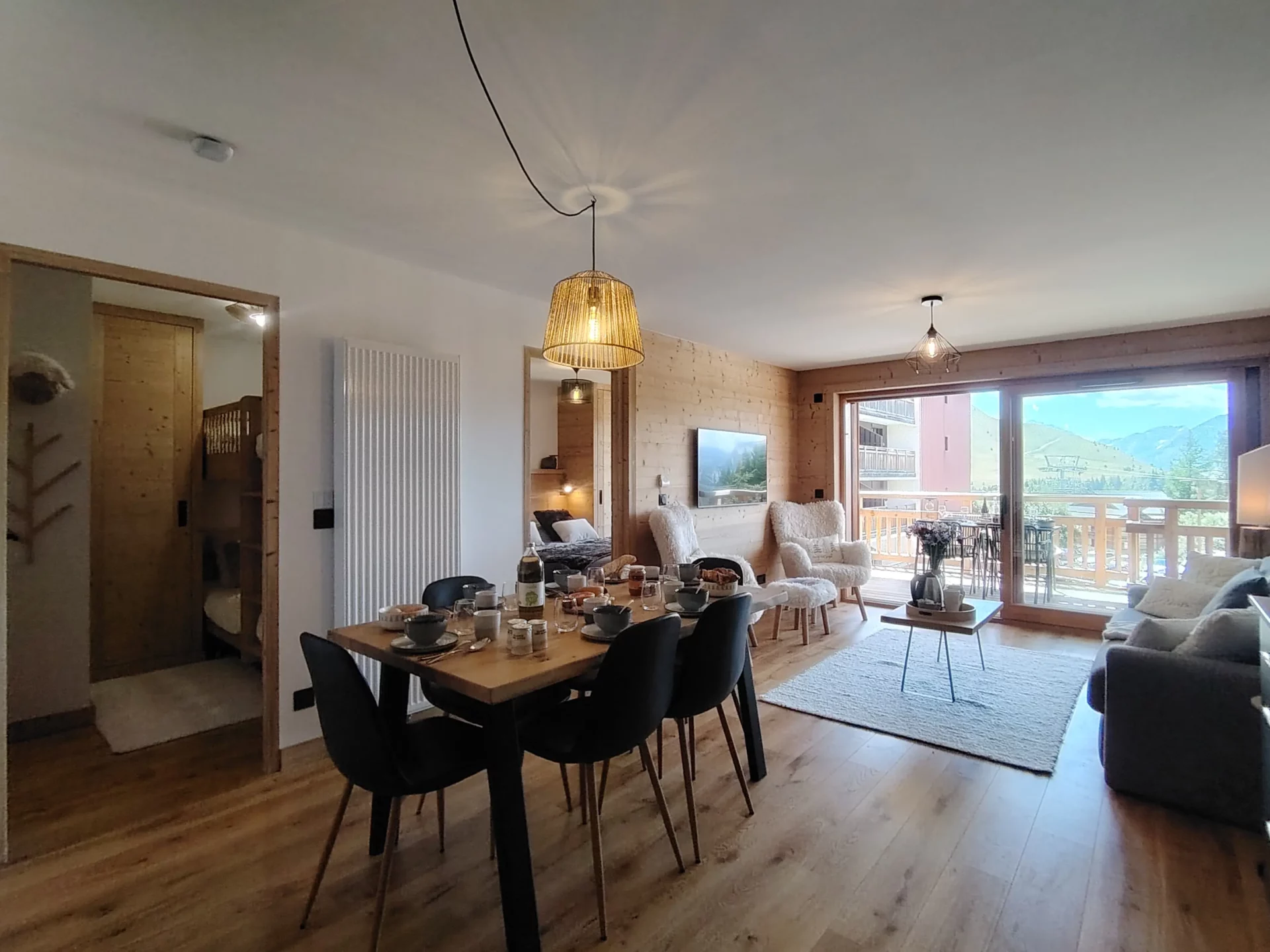 Location appartement à l'alpe d'huez avec table de salle à manger dressée et salon dans l'arrière plan