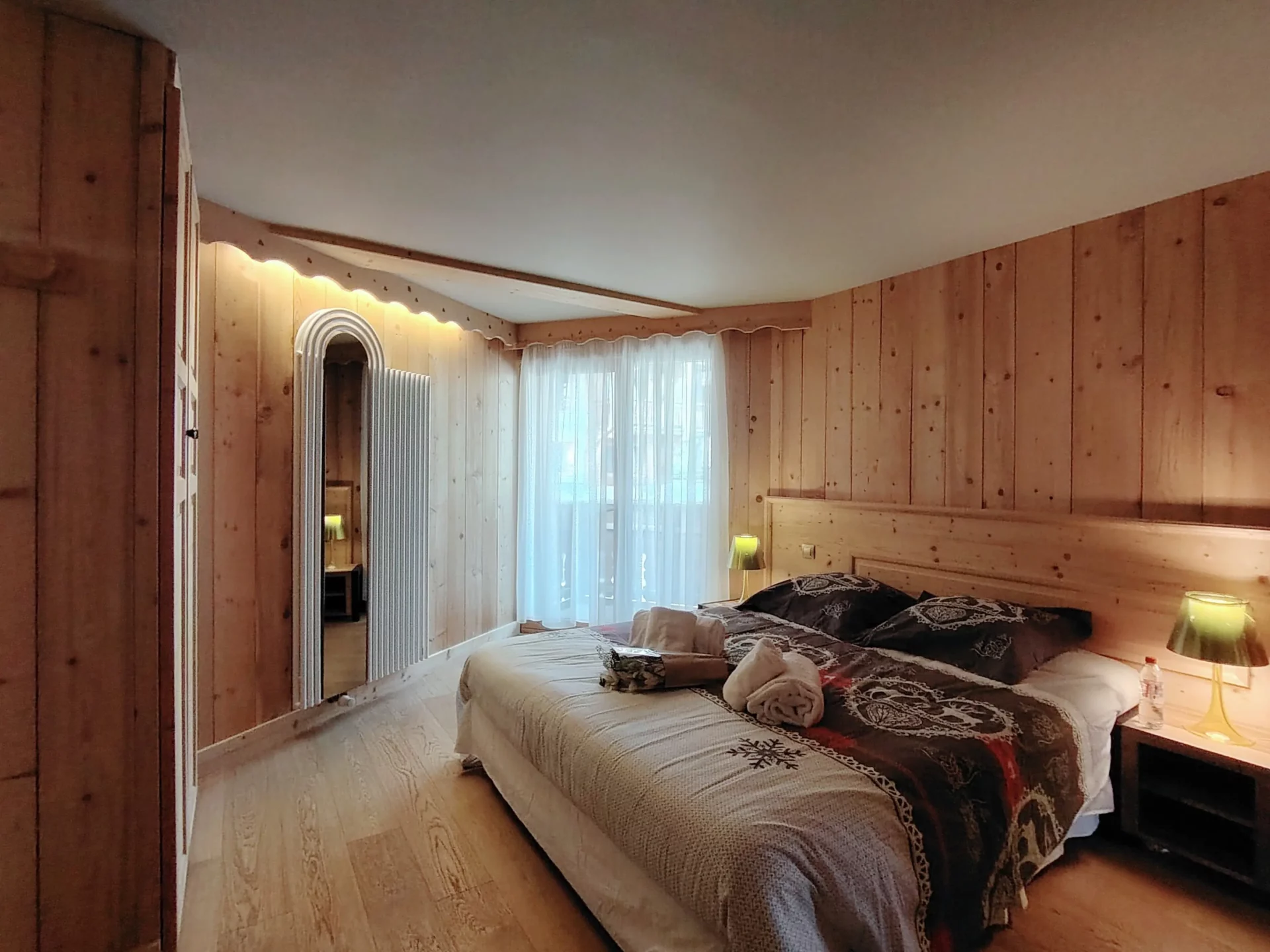 Chambre double chaleureuse de l’appartement Les Alpages à l’Alpe d’Huez, décor bois, lit confortable et lumière naturelle.