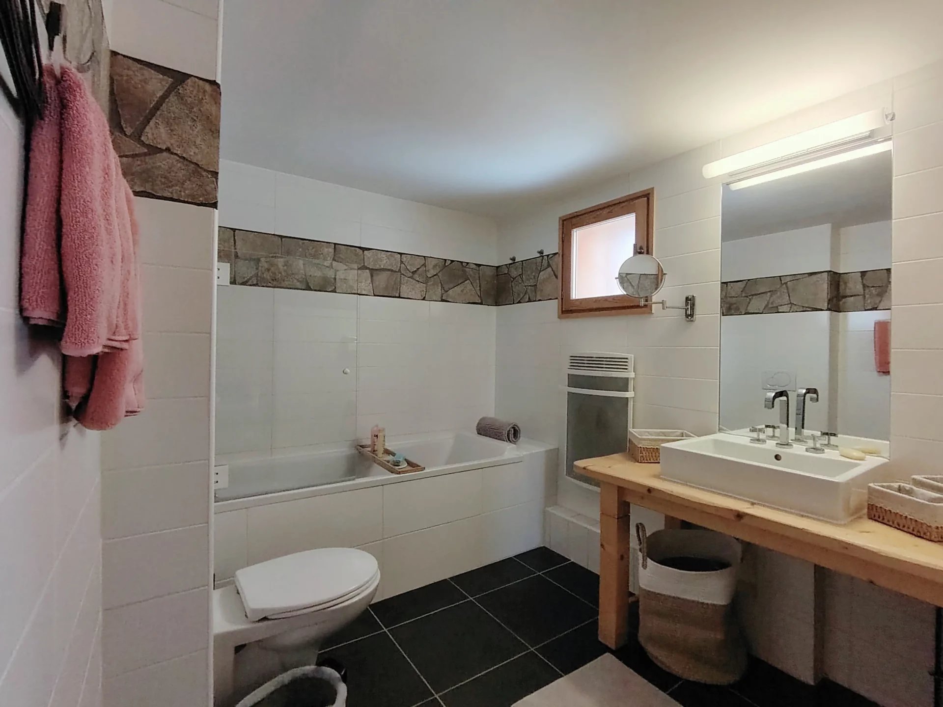 Salle de bain de l’appartement Les Alpages à l’Alpe d’Huez, équipée d’une baignoire, vasque moderne et finitions en pierre