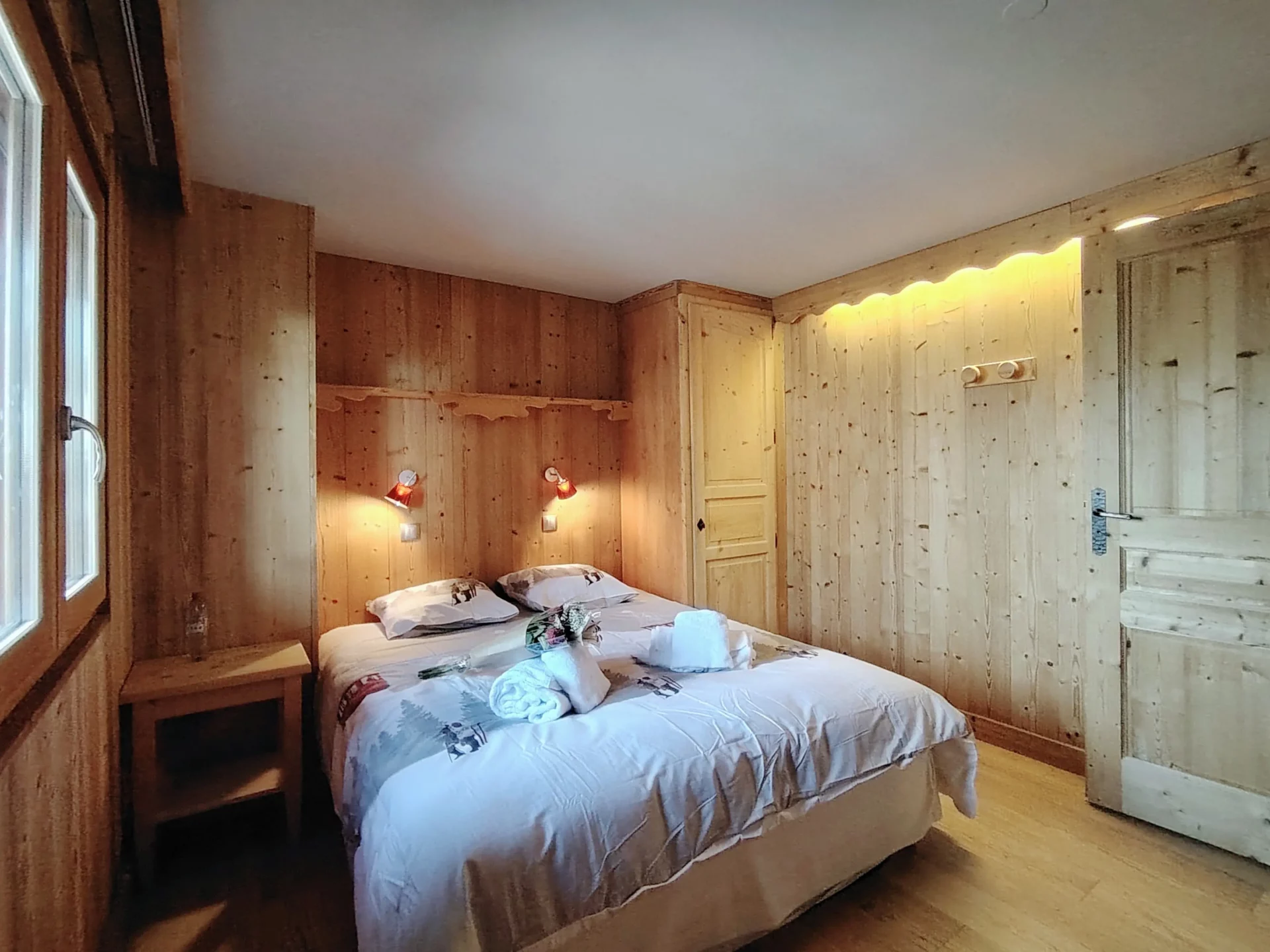 Chambre double cosy de l’appartement Les Alpages à l’Alpe d’Huez, décor bois naturel et lit préparé avec linge de maison