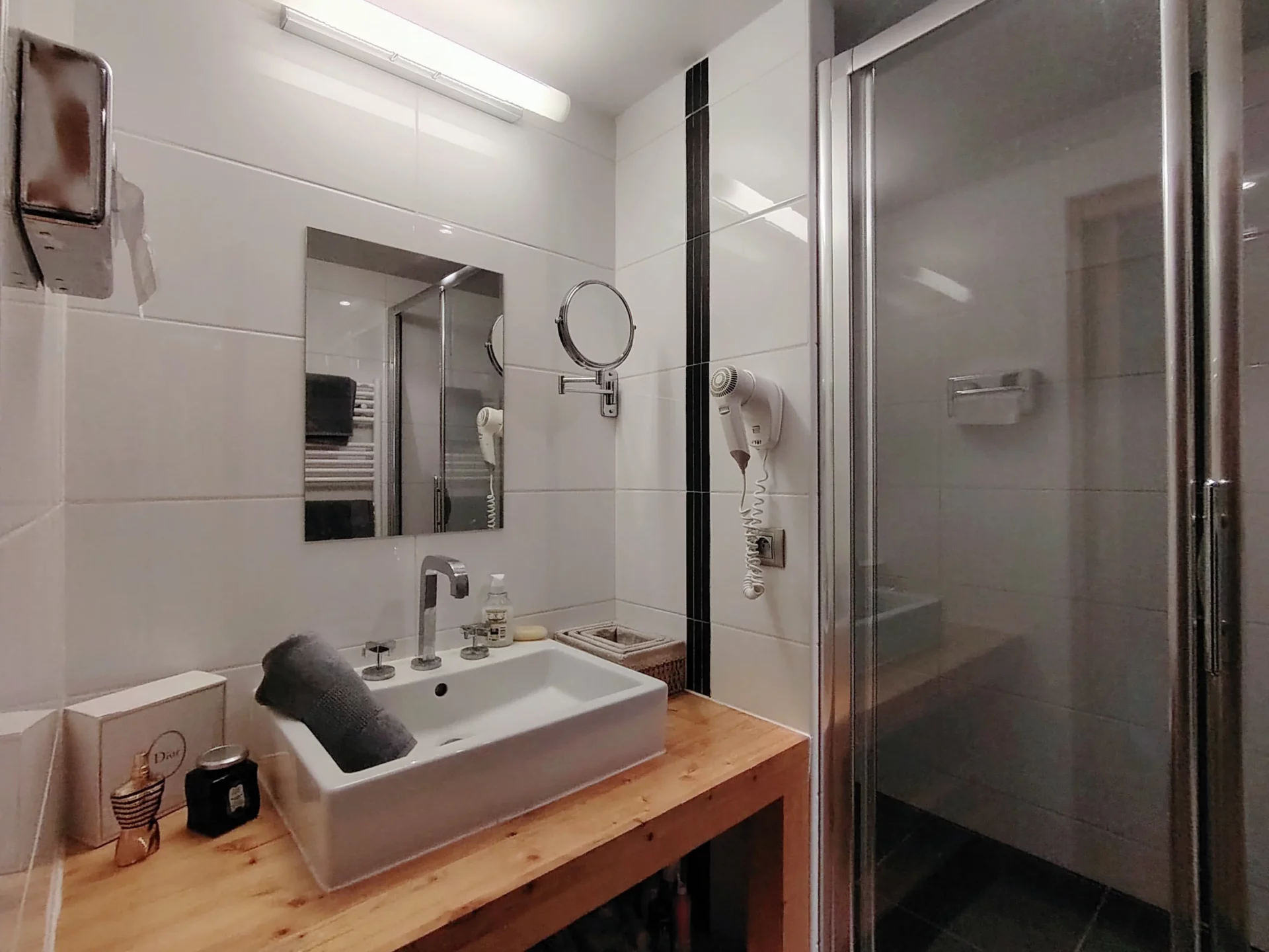 Salle d’eau élégante de l’appartement Les Alpages à l’Alpe d’Huez, avec douche vitrée, lavabo moderne et plan en bois naturel
