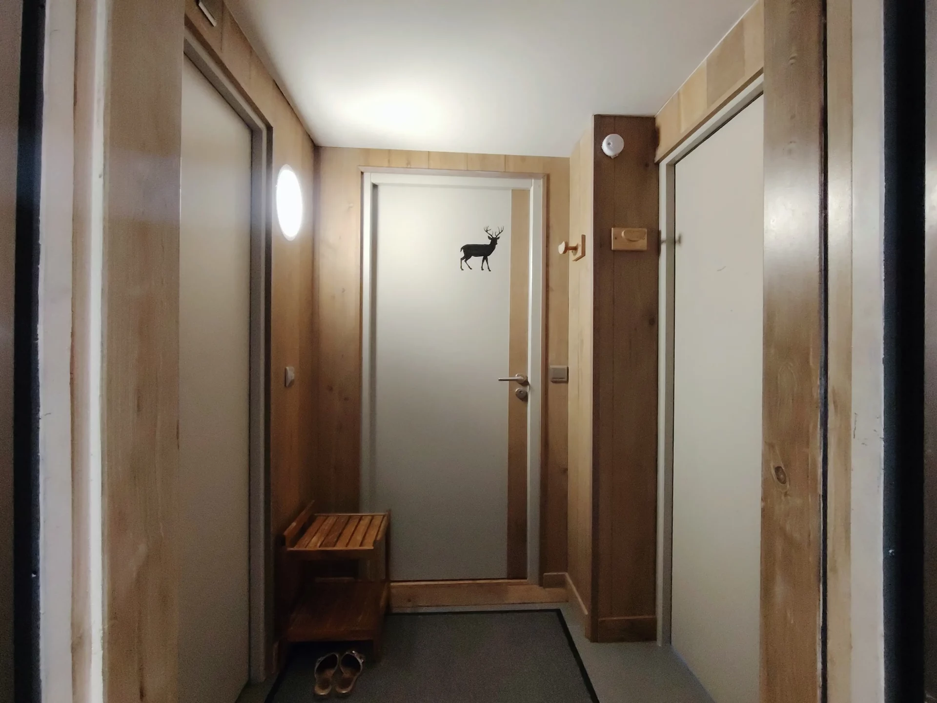 Palier de l’appartement Les Alpages à l’Alpe d’Huez, ambiance chalet en bois clair, donnant accès aux chambres et salles de bain.