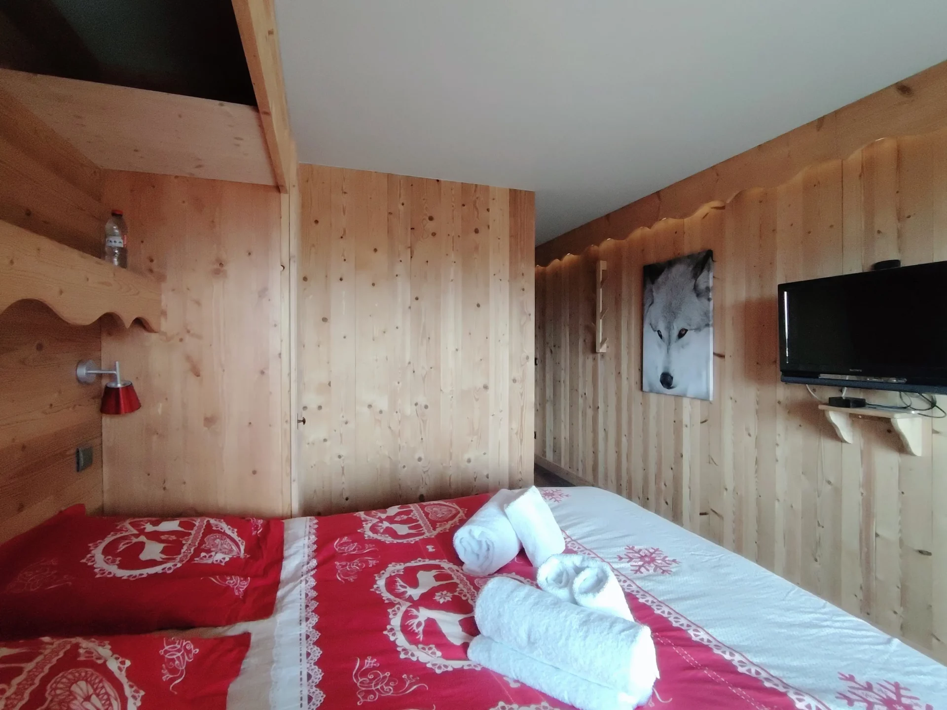 Chambre de l’appartement Les Alpages à l’Alpe d’Huez avec lit double, TV murale, décoration alpine et linge de maison fourni