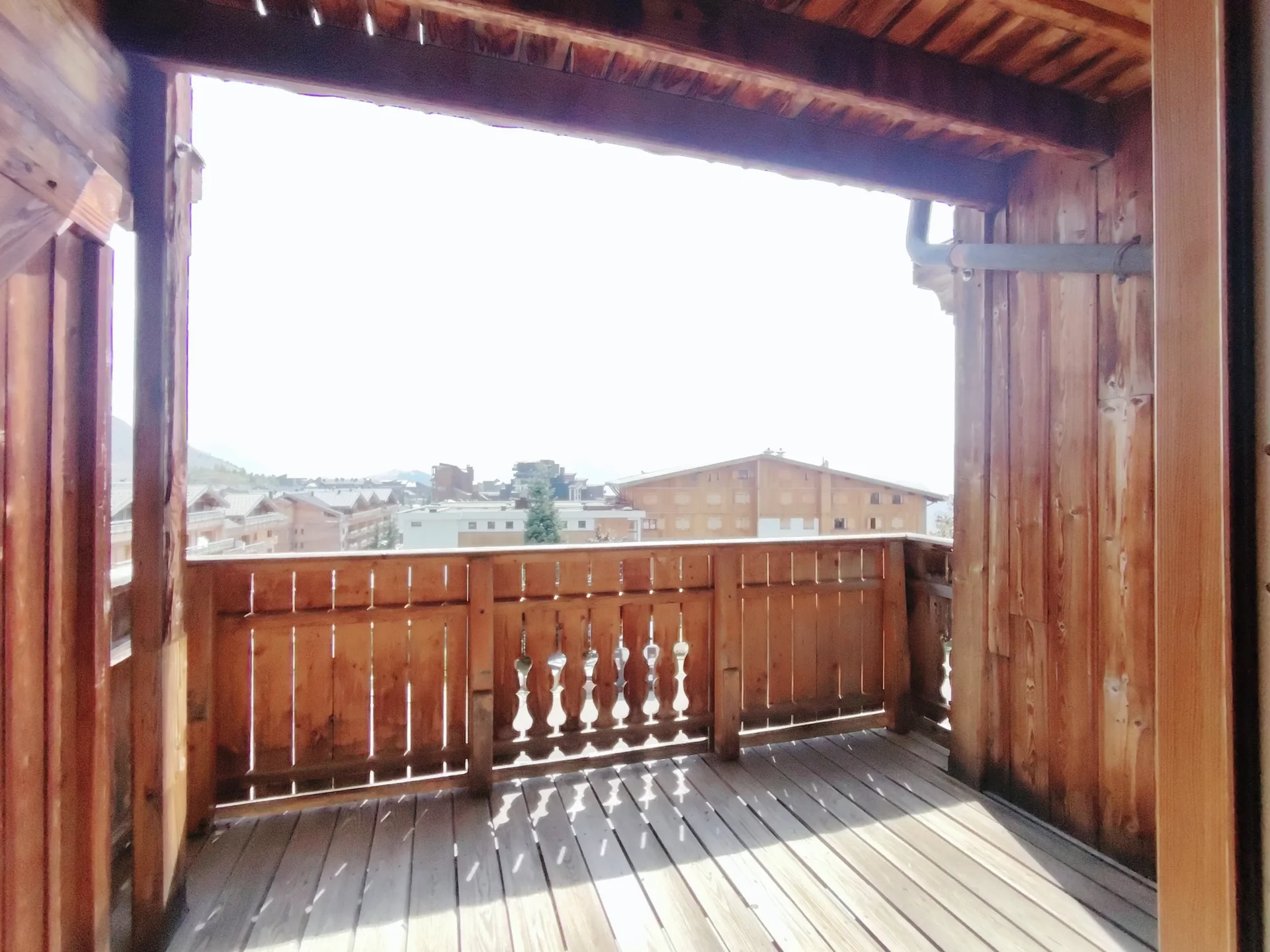 Balcon privatif de l’appartement Les Alpages à l’Alpe d’Huez, en bois traditionnel, offrant une belle vue sur les Alpes