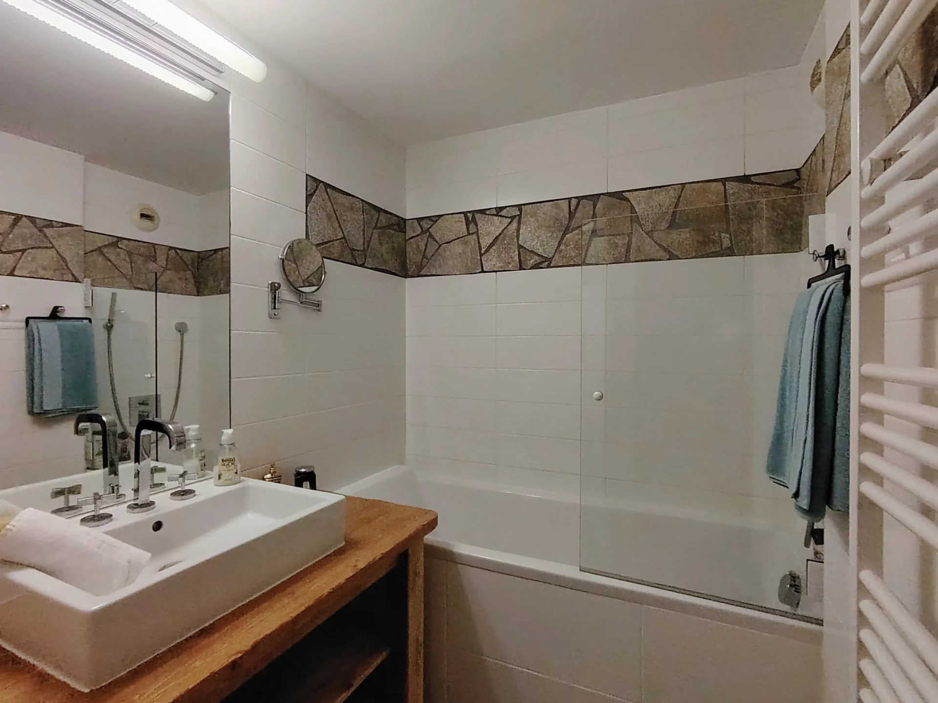 Salle de bain élégante de l’appartement Les Alpages à l’Alpe d’Huez avec vasque moderne, baignoire et décor en pierre naturelle