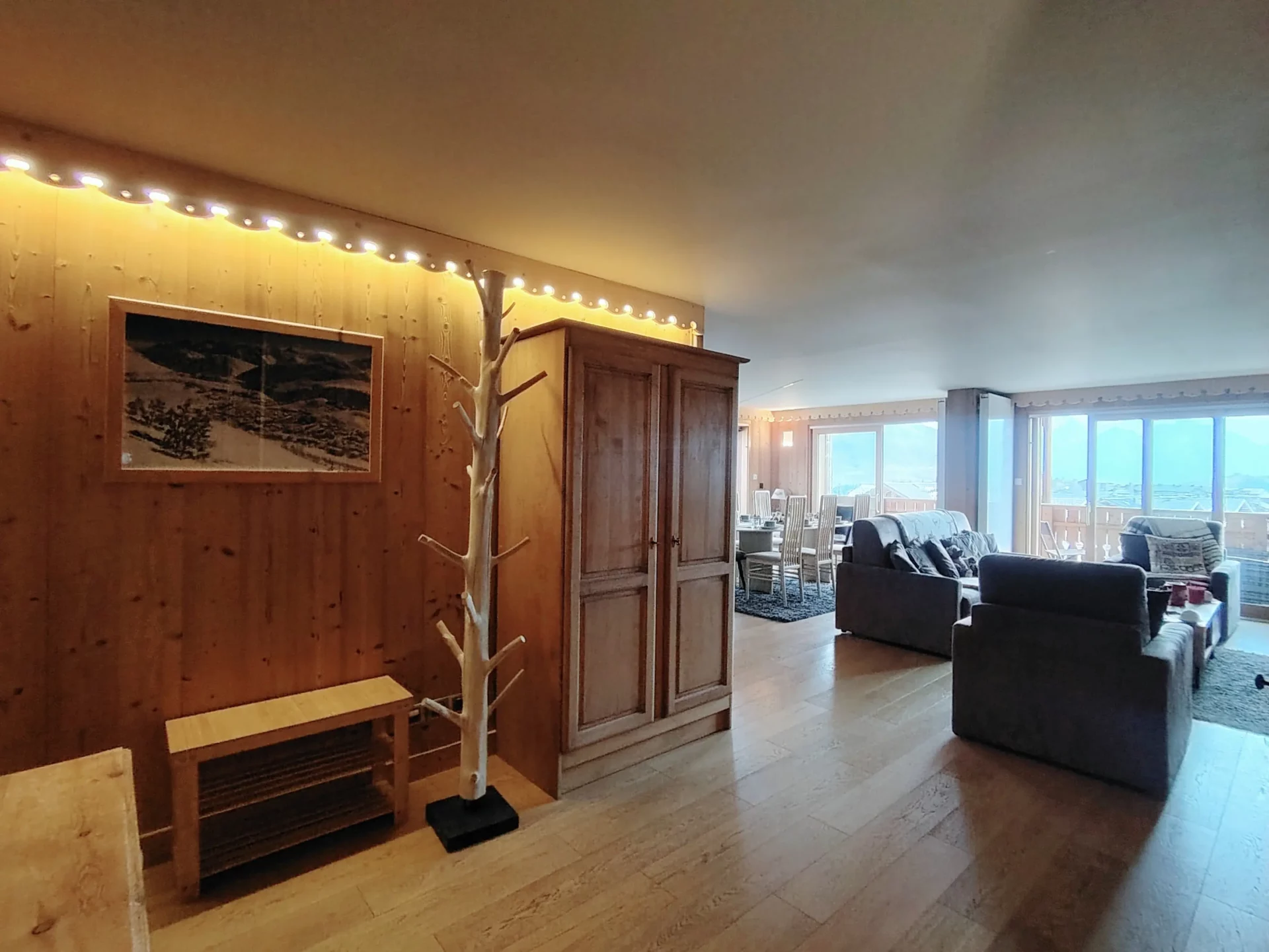 Entrée de l’appartement Les Alpages à l’Alpe d’Huez avec vue sur le grand salon et la salle à manger baignés de lumière
