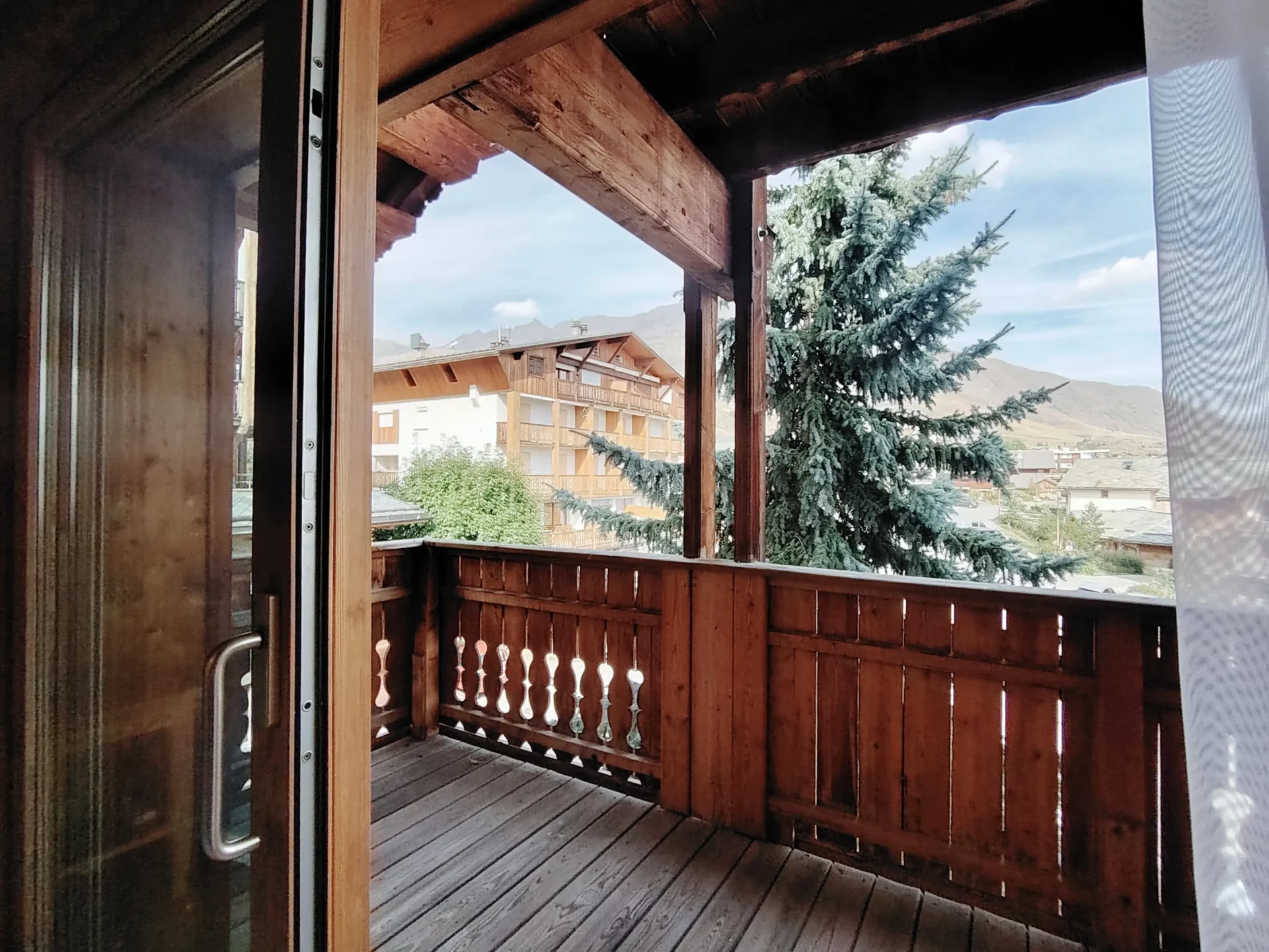 Balcon privé de l’appartement Les Alpages à l’Alpe d’Huez, offrant une belle vue sur les chalets et les Alpes.