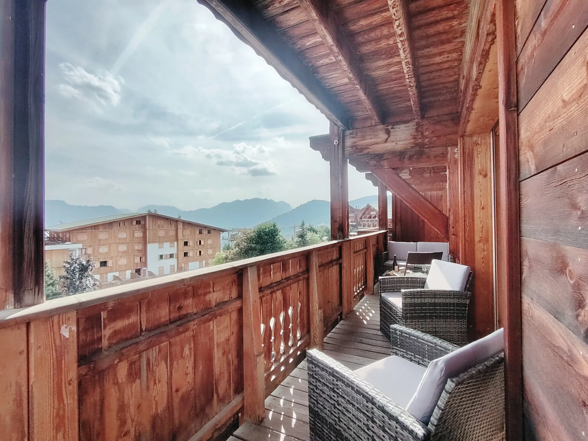Balcon en bois traditionnel de l’appartement Les Alpages à l’Alpe d’Huez, offrant plusieurs espaces détente avec fauteuils extérieurs