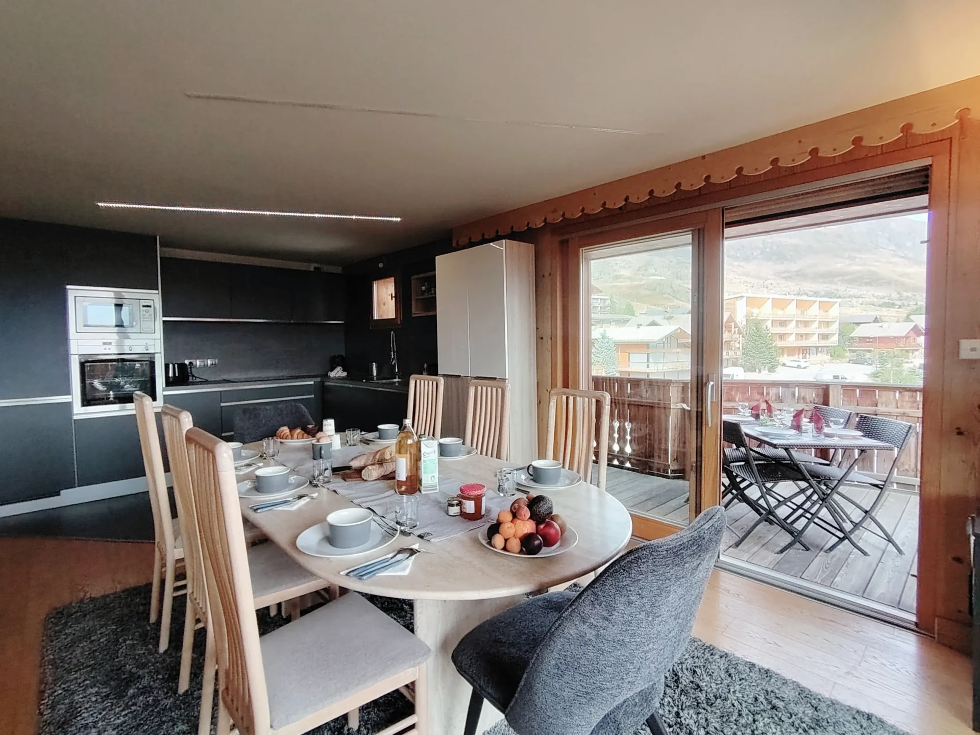 Cuisine équipée et salle à manger conviviale de l’appartement Les Alpages à l’Alpe d’Huez, avec accès direct à la terrasse vue montagne.