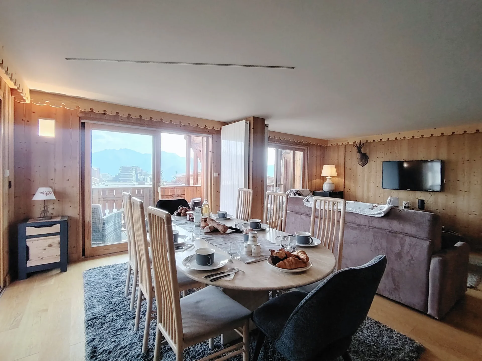 Salle à manger lumineuse de l’appartement Les Alpages à l’Alpe d’Huez, donnant sur la terrasse et offrant une superbe vue sur les Alpes