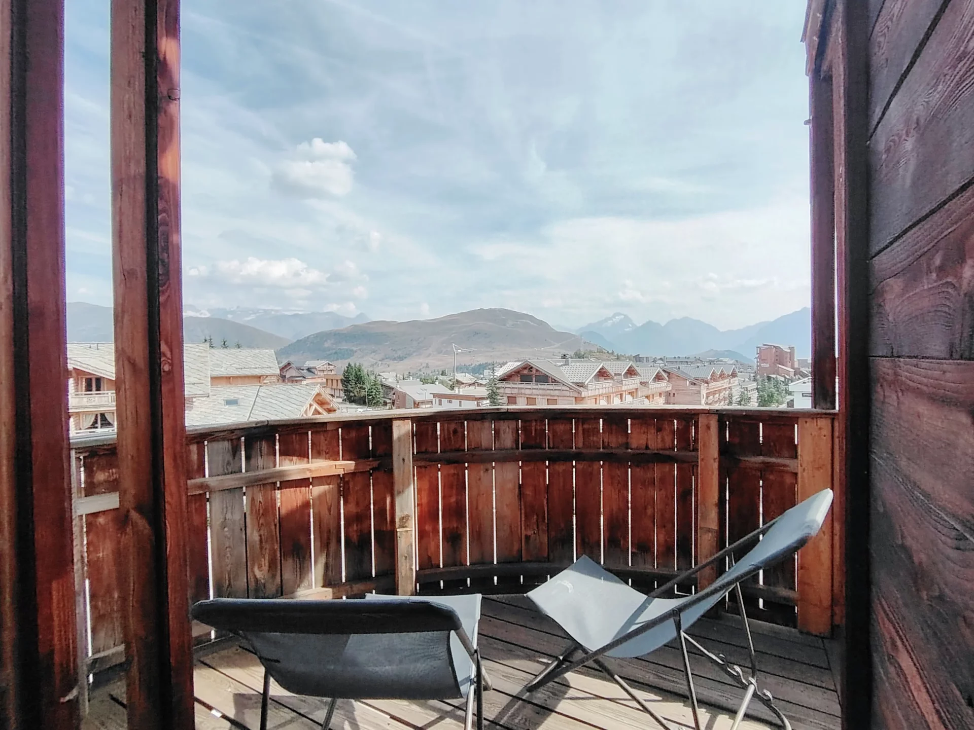 Terrasse ensoleillée de l’appartement Les Alpages à l’Alpe d’Huez, équipée de transats pour profiter d’une vue imprenable sur les Alpes.
