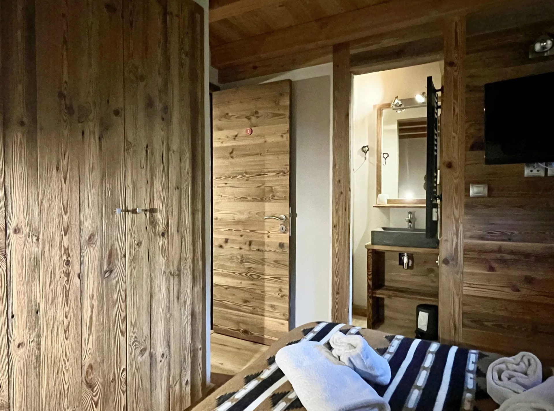 Chambre double avec ambiance chalet et salle de bain attenante.