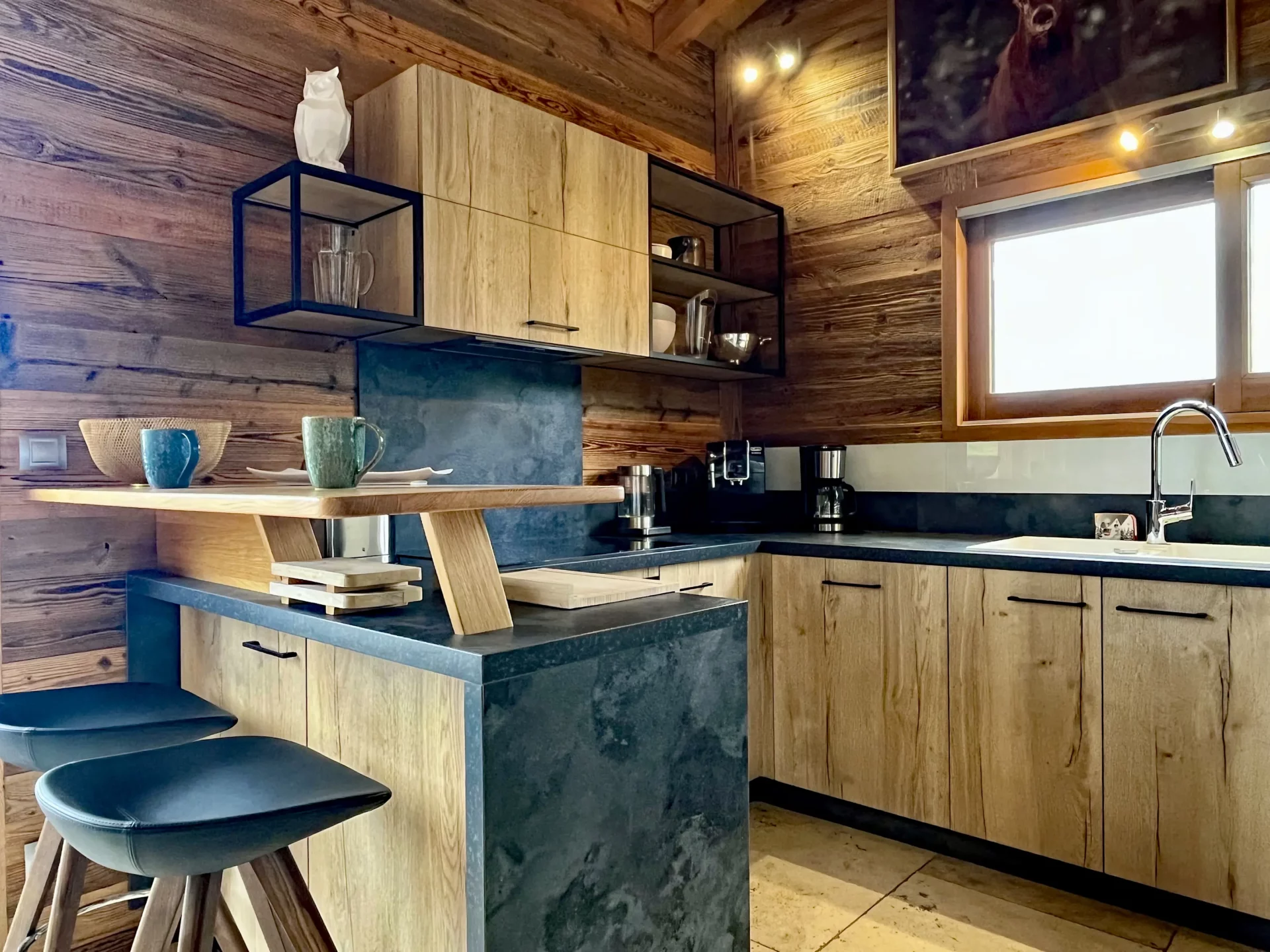 Cuisine moderne équipée avec plan de travail en pierre et meubles boisés – Location prestige Alpe d’Huez