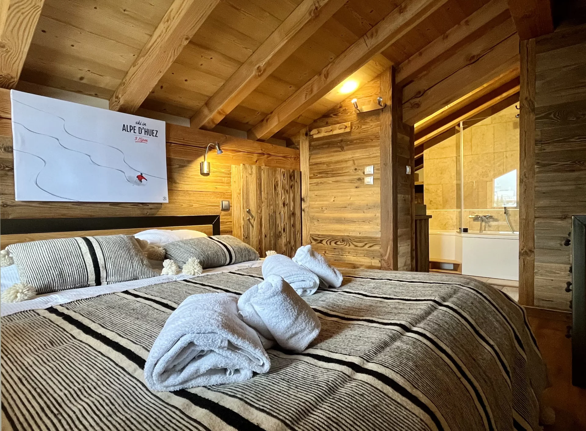 À l’étage de notre location appartement Alpe d’Huez, la suite parentale sous les toits offre une atmosphère intime et cosy avec sa salle de bain privative.