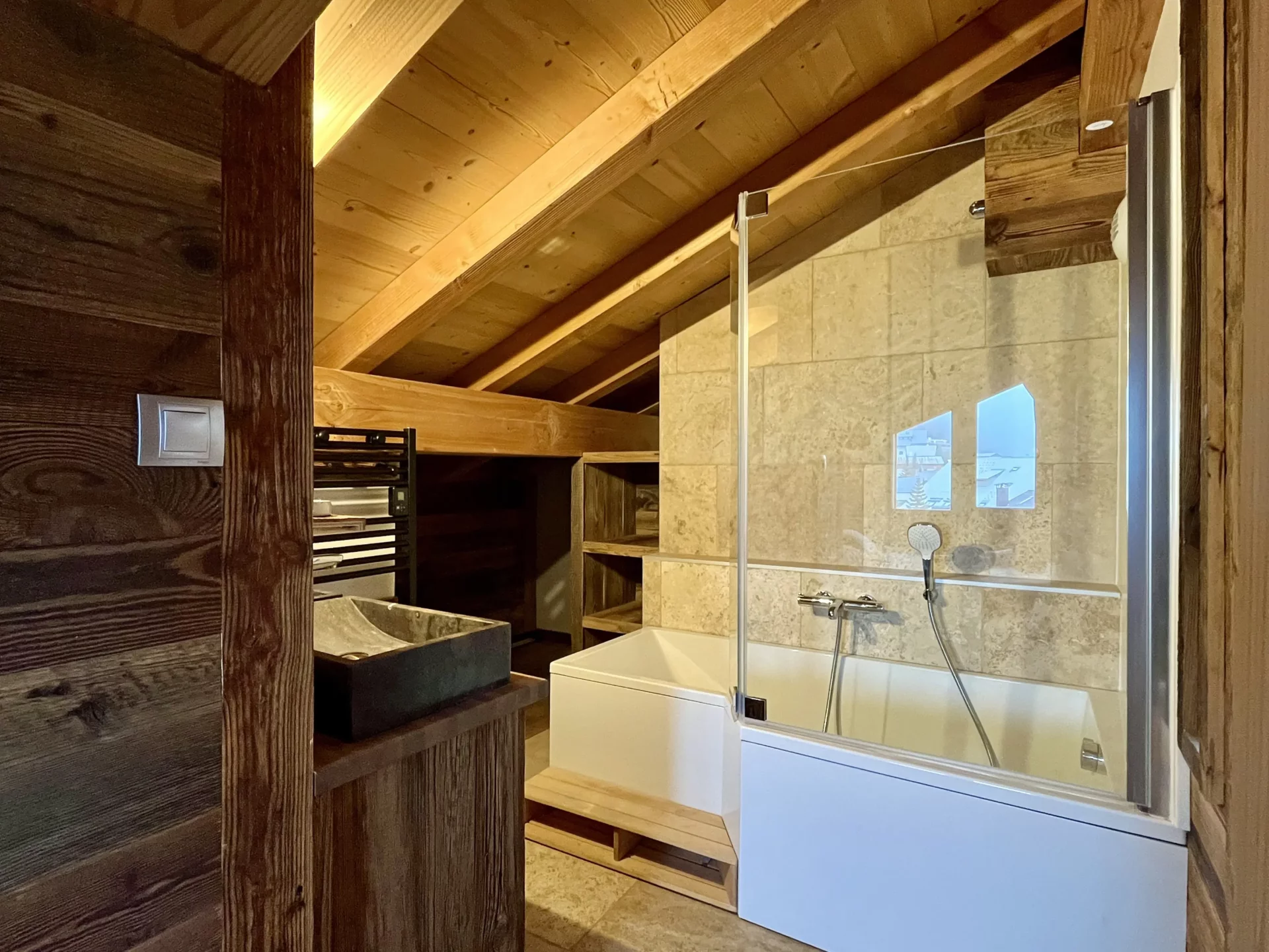 Notre location appartement Alpe d’Huez dispose d’une salle de bain moderne avec baignoire, mêlant pierre naturelle et bois alpin, parfaite pour se détendre après le ski.