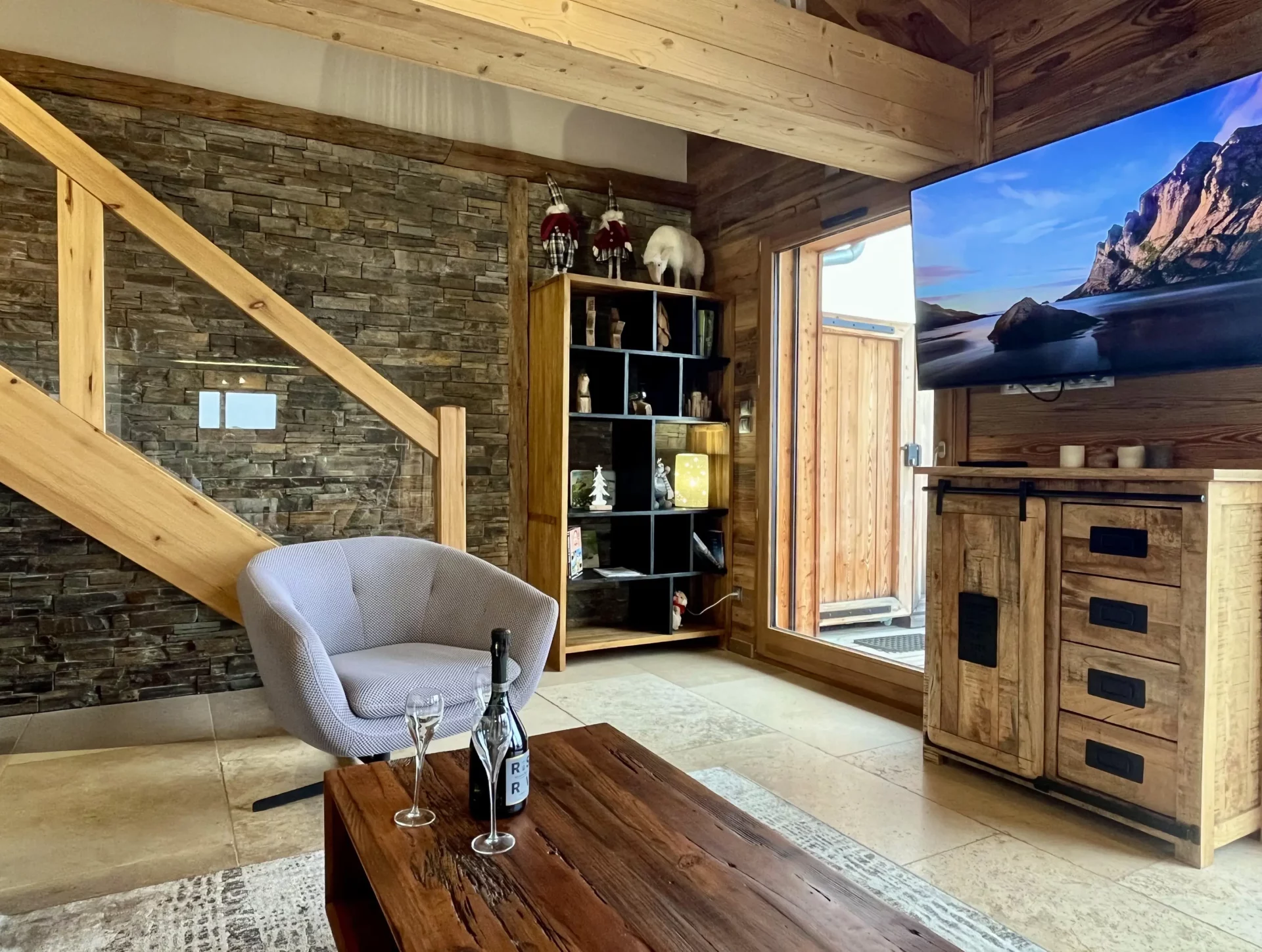 Depuis le séjour de notre location chalet Alpe d’Huez, profitez d’une vue exceptionnelle sur les montagnes grâce à de larges baies vitrées donnant accès à la terrasse.