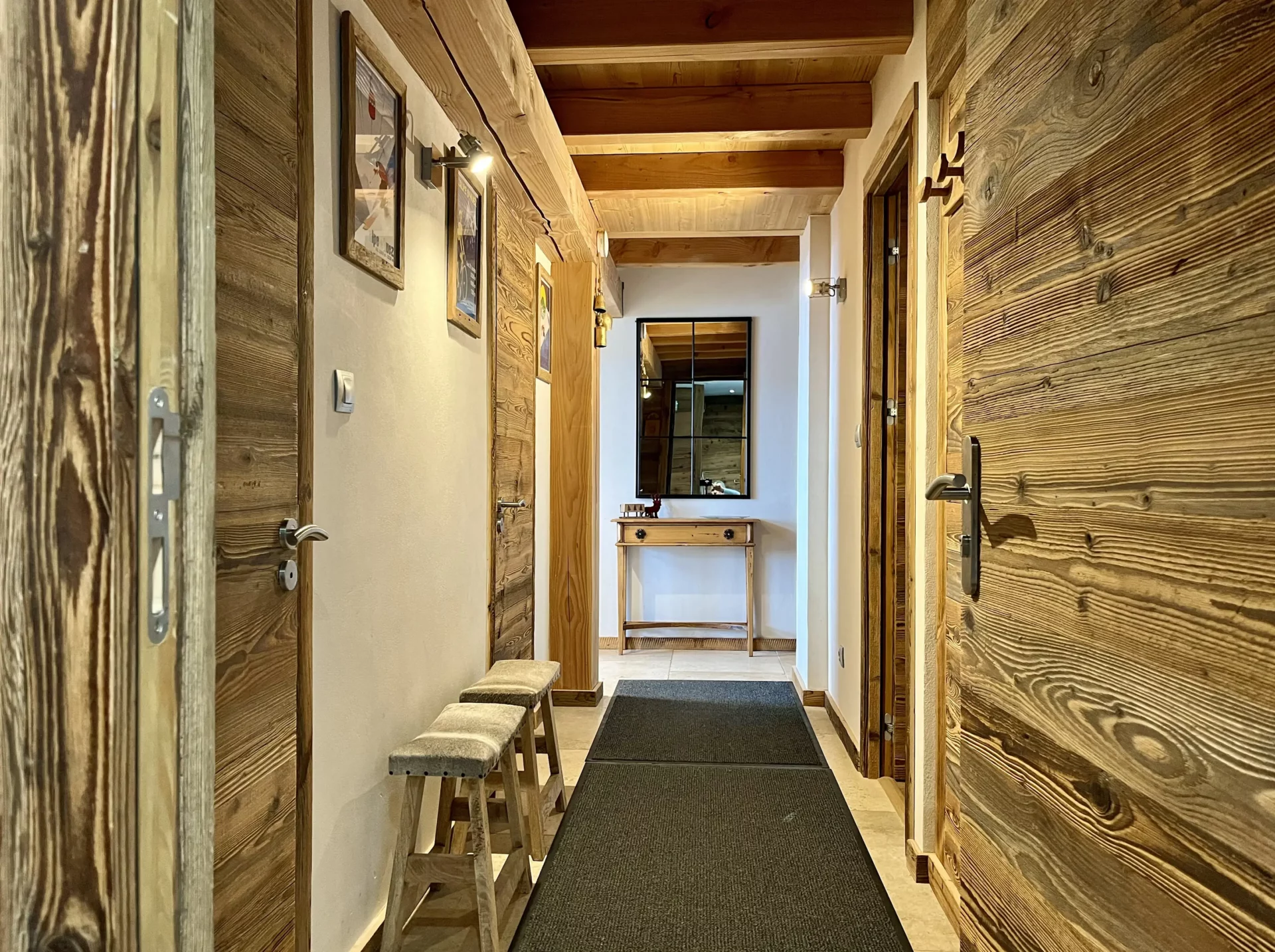 La location chalet Alpe d’Huez s’ouvre sur un couloir accueillant, décoré dans l’esprit alpin, avec accès direct aux chambres parentales.