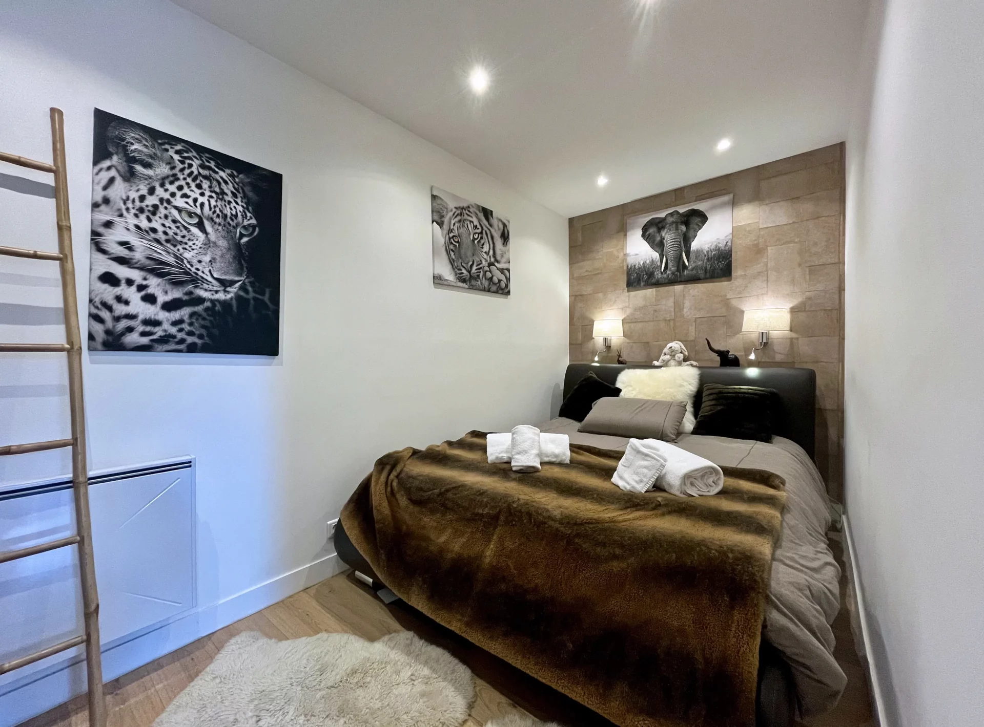 Chambre principale du Chalet Isba décorée avec des tableaux d’animaux sauvages, murs clairs et ambiance cocooning avec linge de lit chaud.
