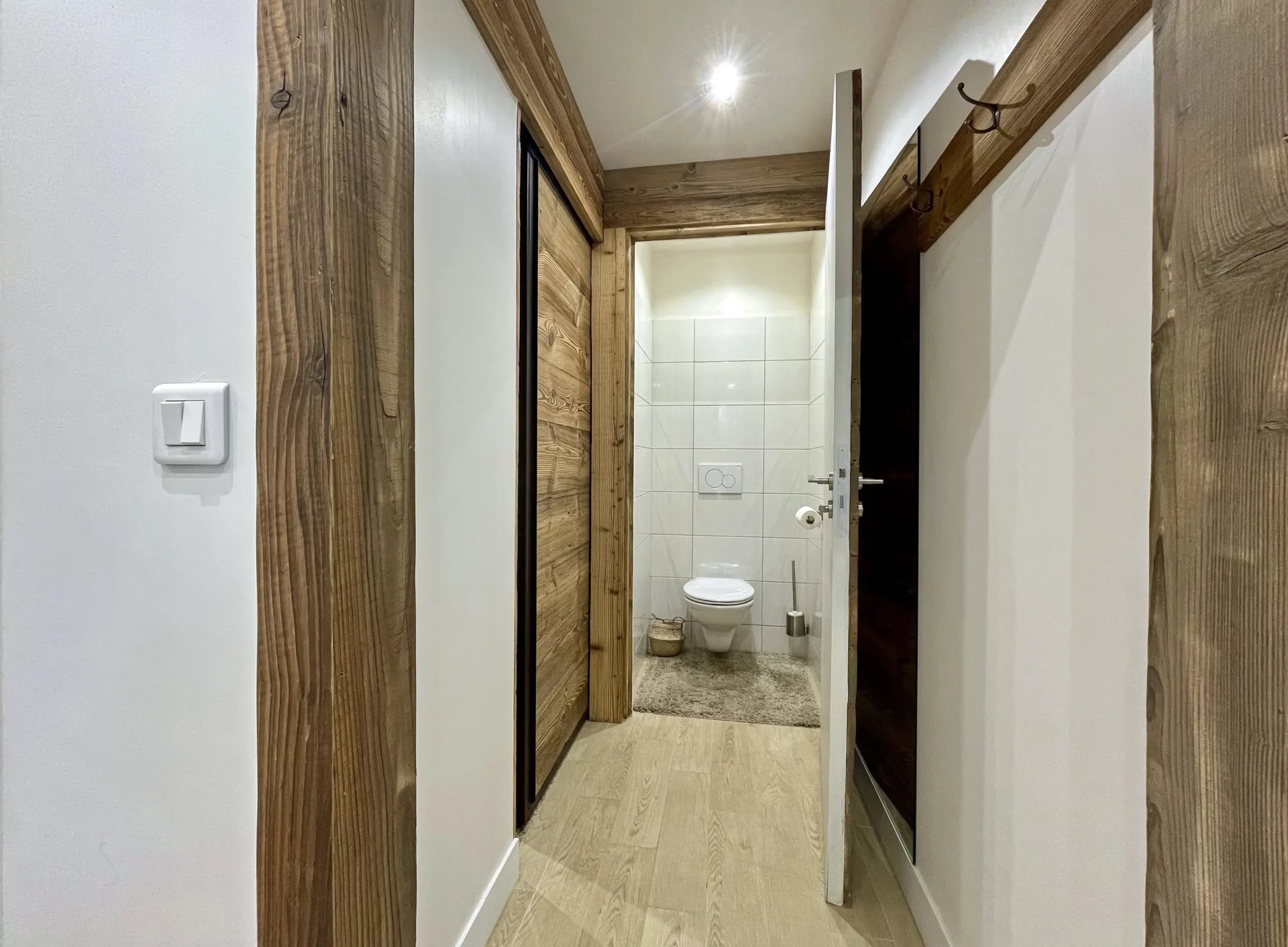 Toilettes indépendantes du Chalet Isba à l’Alpe d’Huez, décor épuré avec murs blancs et touches de bois naturel.