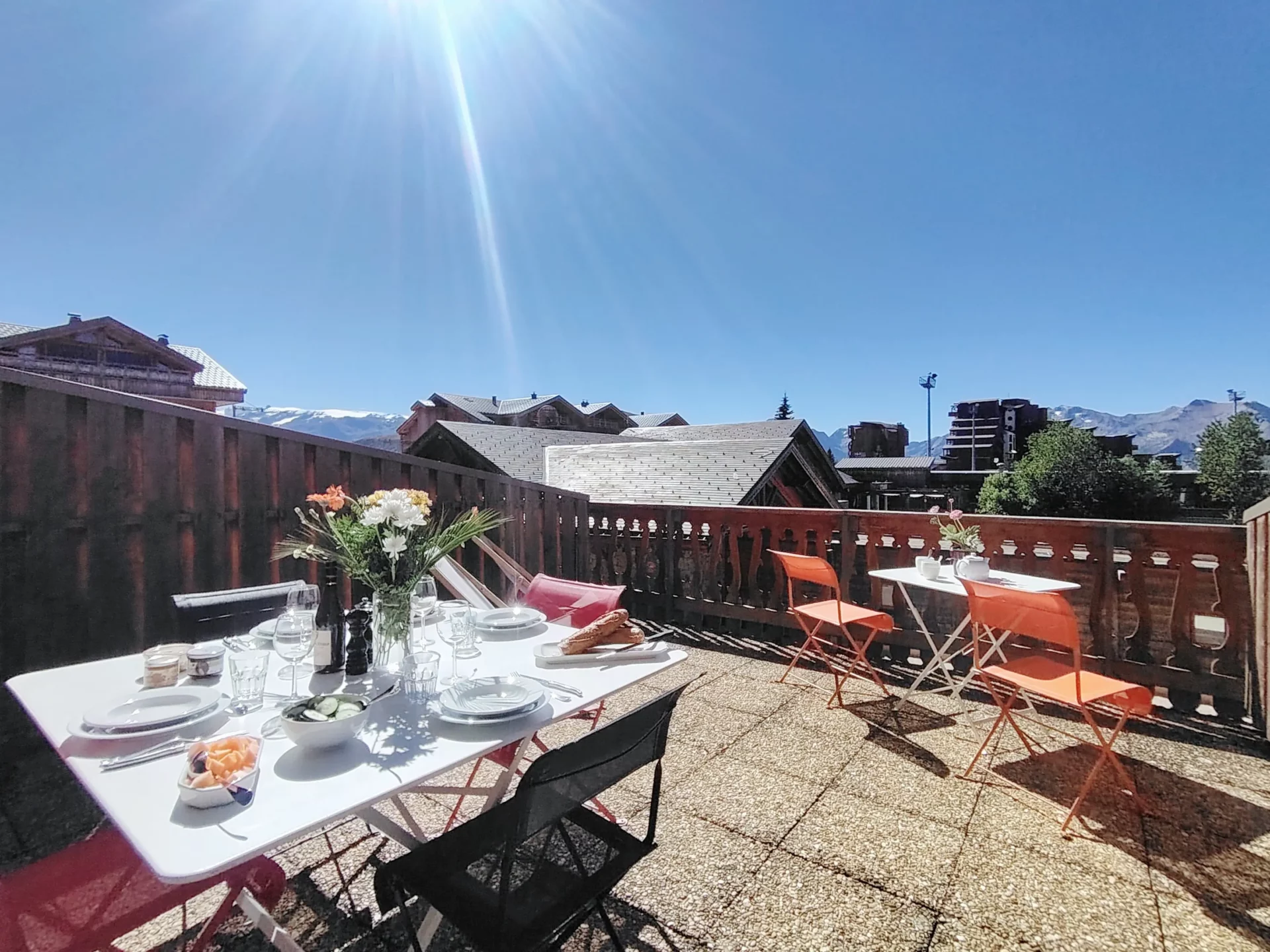 Grande terrasse ensoleillée de l’appartement Résidence Ménandière à l’Alpe d’Huez, aménagée avec table dressée et vue sur les montagnes.