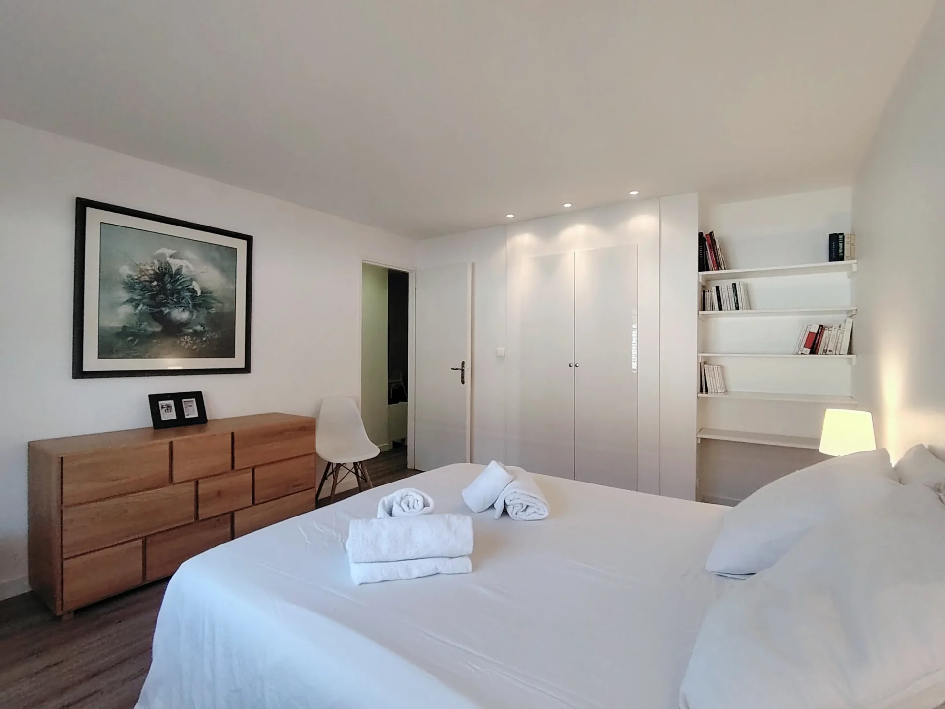 Chambre parentale élégante avec lit double, commode en bois clair et décoration murale.