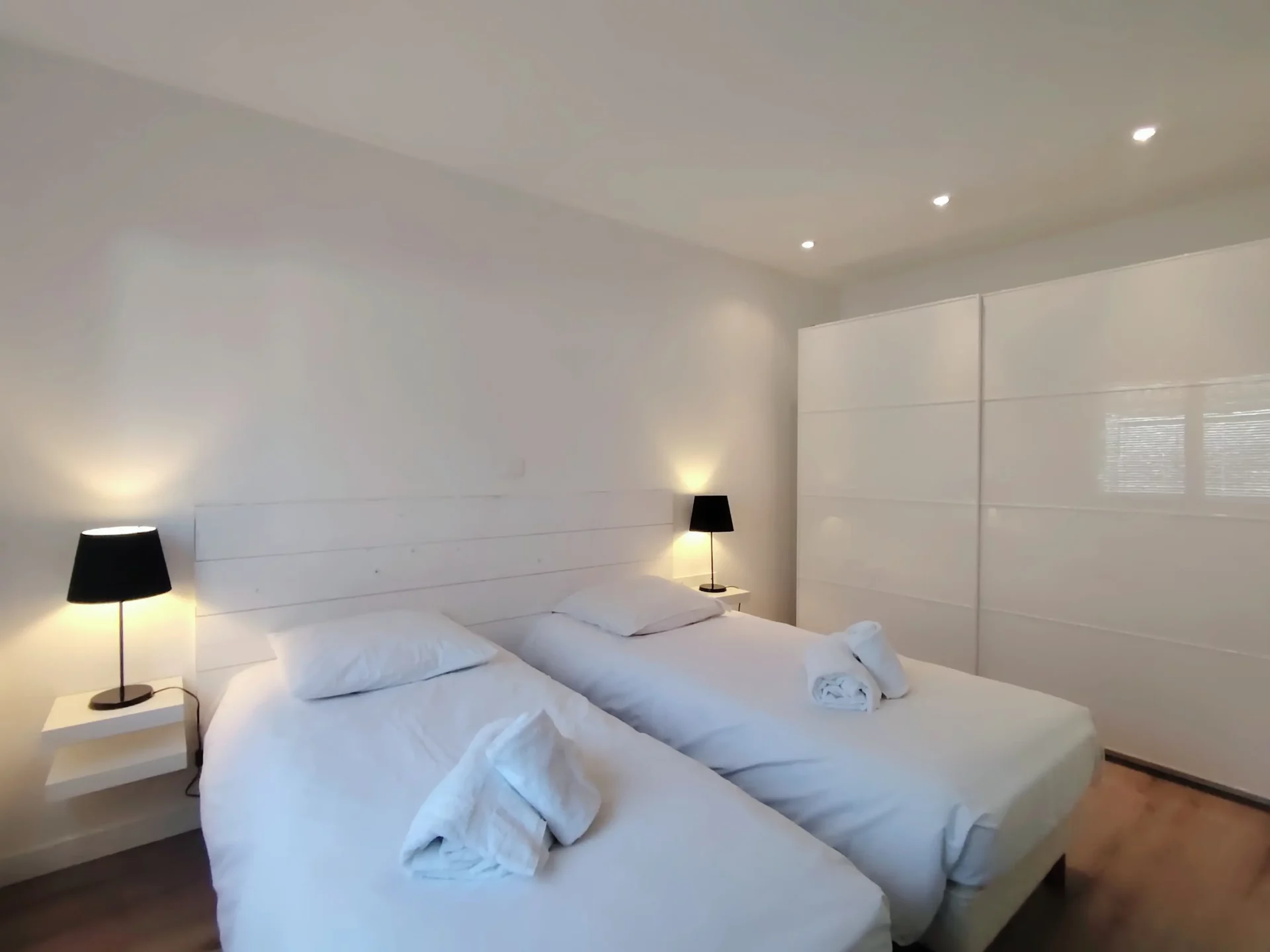 Chambre avec deux lits simples séparés, tables de chevet et grands rangements intégrés.