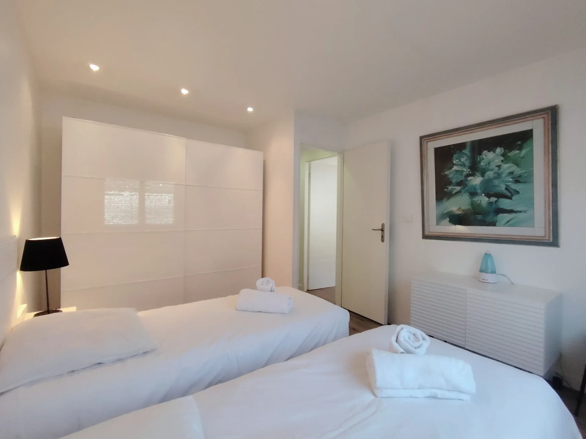 Chambre twin avec deux lits simples et mobilier moderne, idéale pour enfants ou amis.