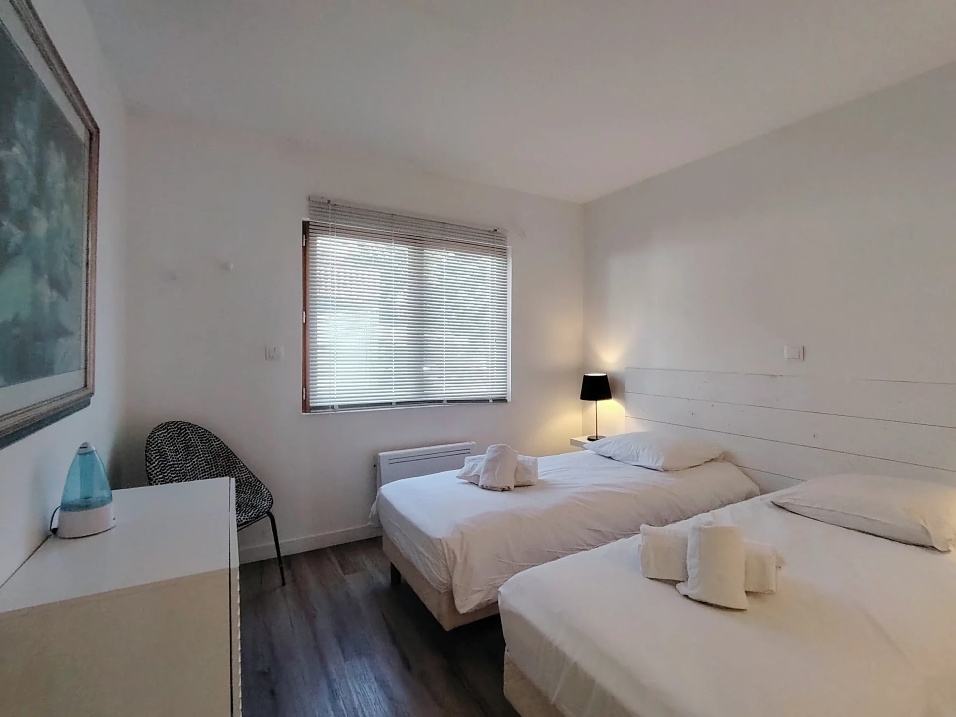 Vue sur la chambre twin lumineuse avec deux lits simples et fenêtre donnant sur l’extérieur.