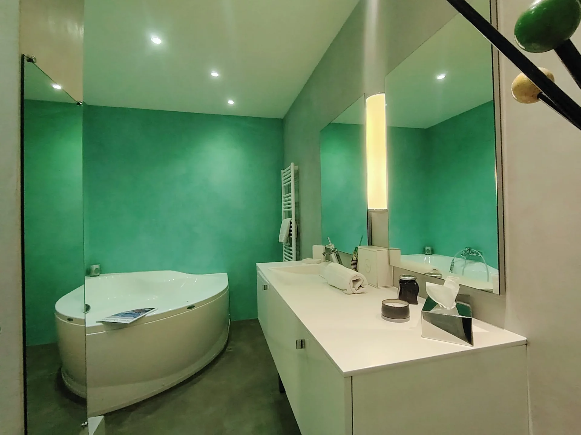Salle de bain contemporaine avec baignoire balnéo, double vasque et murs aux tons vert et gris.