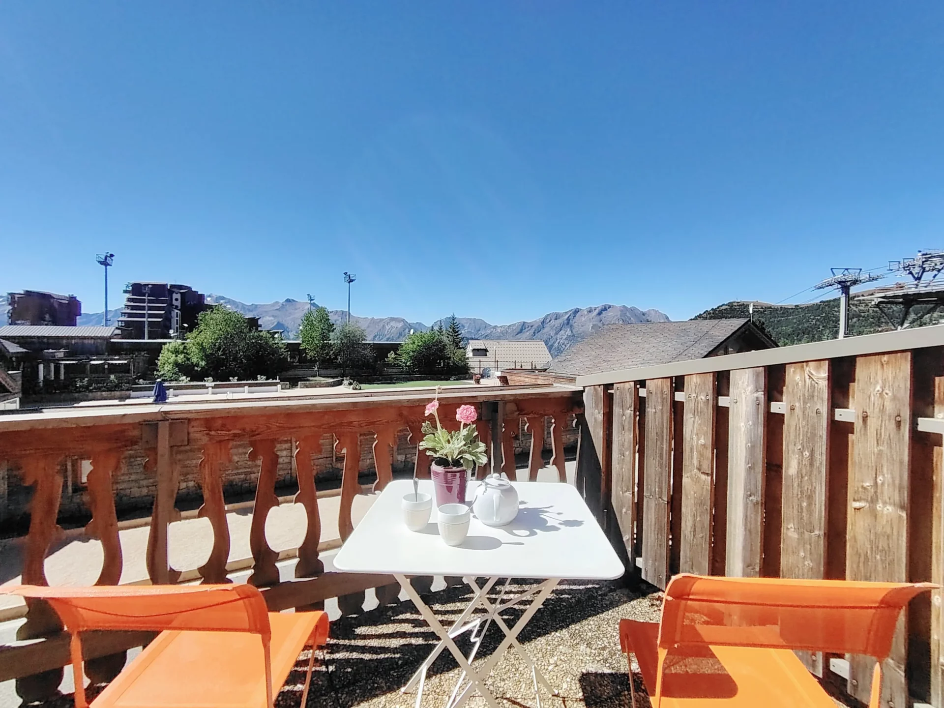 Terrasse de l’appartement Résidence Ménandière à l’Alpe d’Huez avec vue dégagée sur les montagnes et mobilier de jardin.