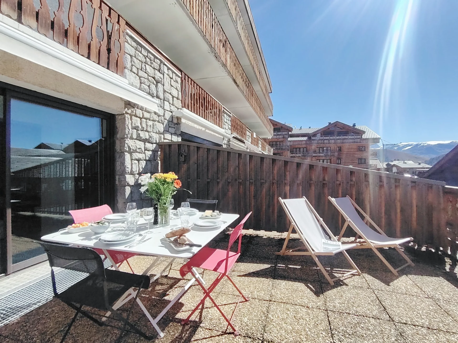 Terrasse spacieuse orientée sud avec transats et table à manger, location vacances Alpe d’Huez