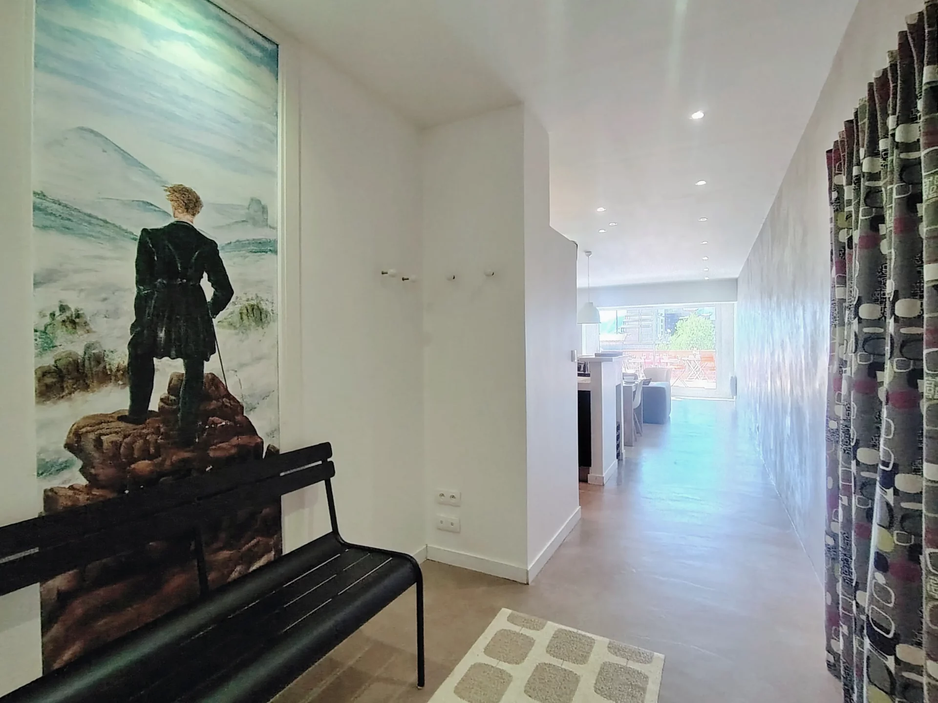 Entrée de l’appartement avec décoration murale artistique et vue sur la pièce de vie lumineuse, Résidence Ménandière Alpe d’Huez.