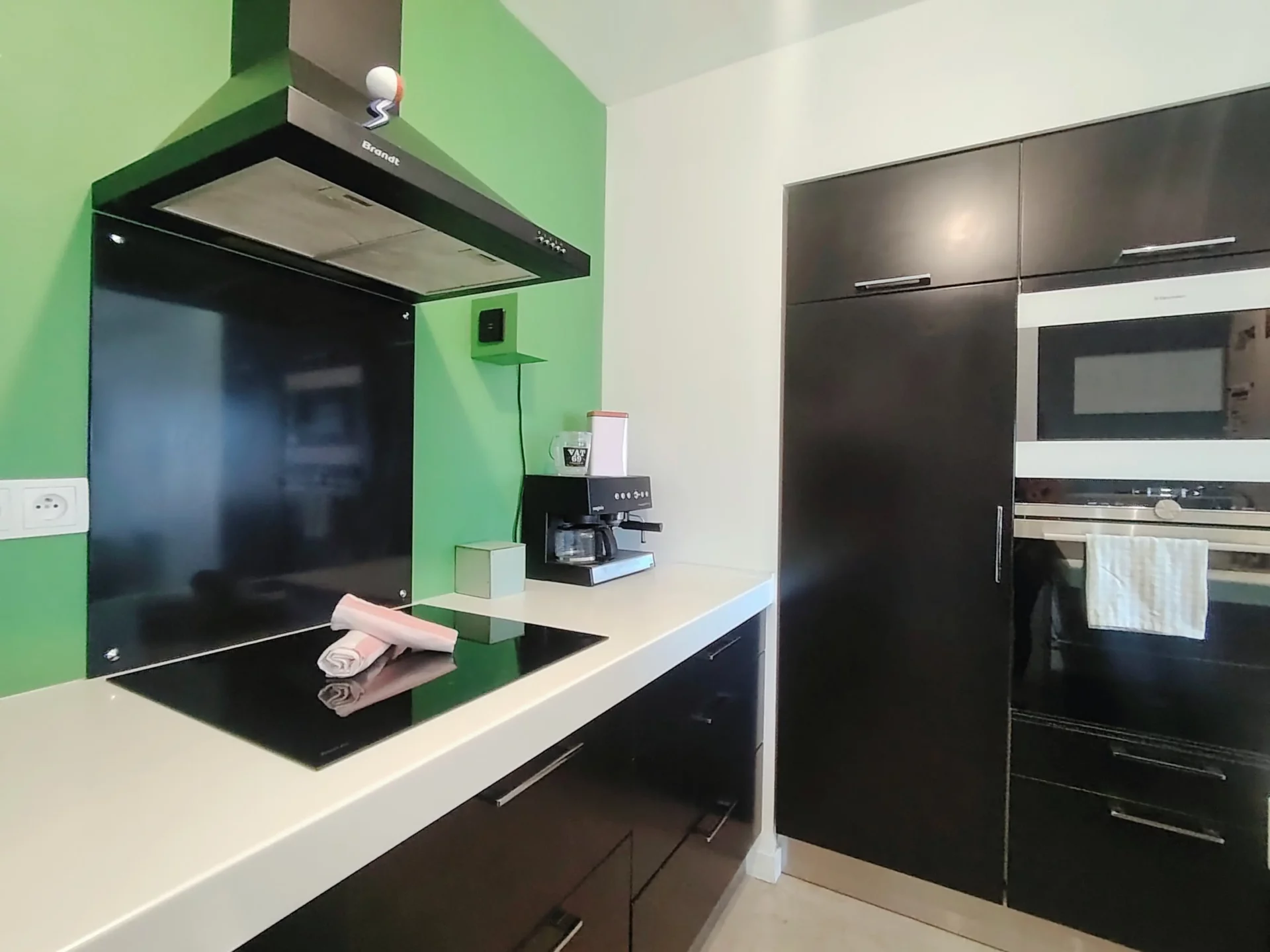 Cuisine design avec four encastré, plaques de cuisson et rangements noirs – appartement Alpe d’Huez