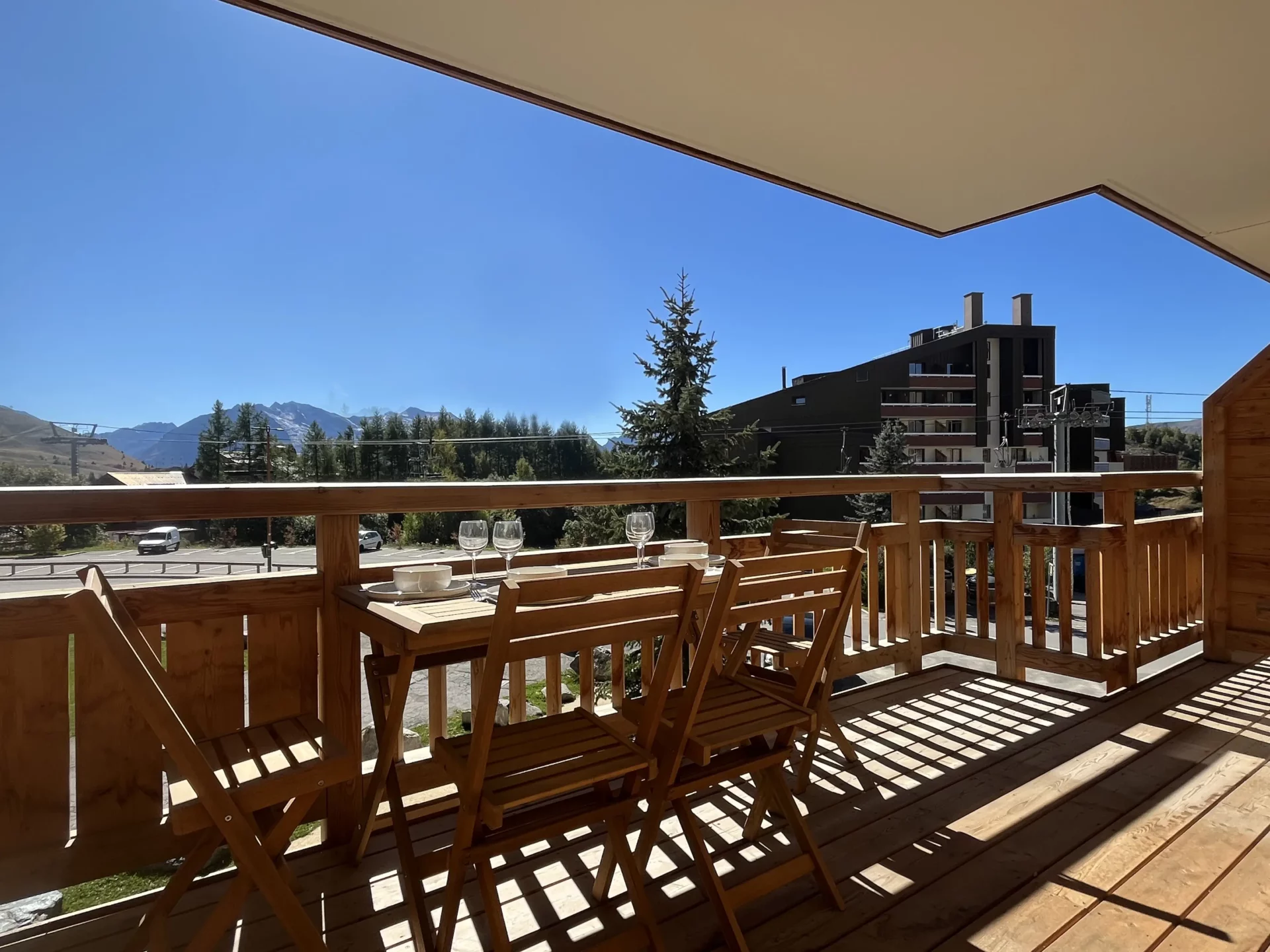 Terrasse orientée sud avec table à manger et belle vue dégagée sur les montagnes et la station de l’Alpe d’Huez.