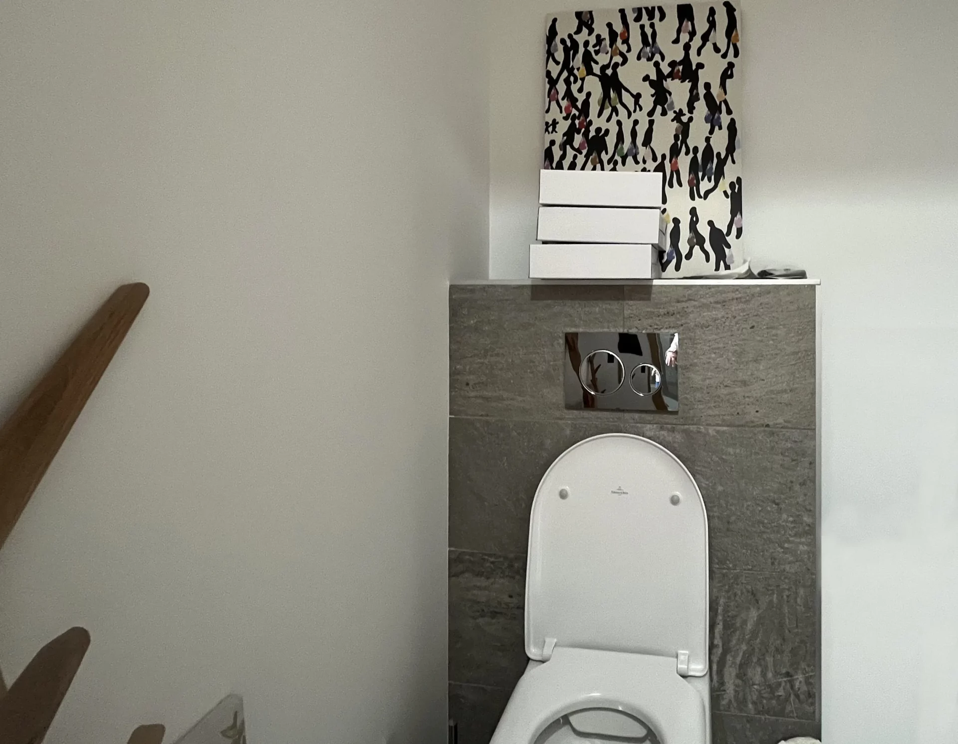 Toilettes modernes avec mur en pierre grise, abattant blanc et décoration murale graphique.