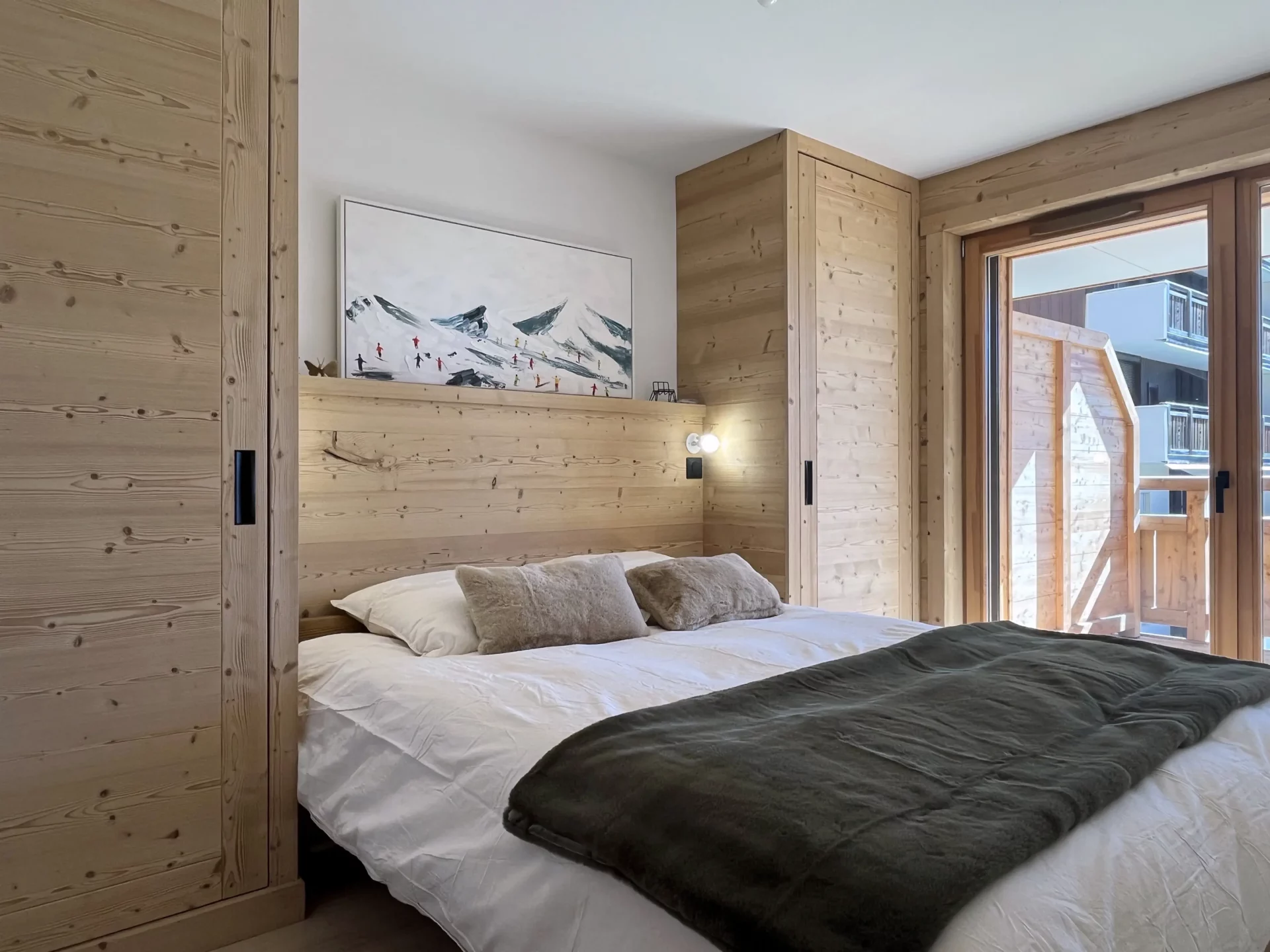 Chambre double cosy avec lit 160x200, bois clair aux murs et accès direct au balcon de l’appartement.
